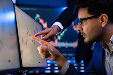 Hisse senedi tüccarı en yüksek hisse senedi piyasasını dinamik değerli analize işaret ediyor. Gerçek zamanlı ekranda iş arkadaşı var. Borsa için finans şirketinde iş birliği yapıyor. Satılabilir.