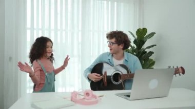 Çekici beyaz bir baba gitar çalarken tatlı bir kız müzik eşliğinde dans ediyor. Mutlu baba ve Amerikalı kız birlikte vakit geçirirken akıllı çocuk müzik yapıyor. Aile eğlence konsepti. Pedagoji.