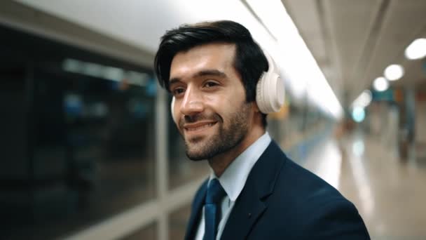 在火车站 聪明的商人戴着耳机打电话 在等待火车或地铁的过程中 专业的执行经理与同事谈论营销策略 膨胀剂 — 图库视频影像