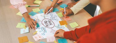 Yaratıcı iş adamları, zihin haritalama kullanarak pazarlama stratejisi ve iş planı hakkında beyin fırtınası yapıyorlar. Girişim ekibi kağıda yazmak için birlikte çalışır. Eline odaklan. - Yakın çekim. Değiştirilmiş.