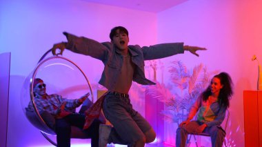 Çok kültürlü bir arkadaş kürsüde otururken Asyalı yetenekli bir dansçı modern müziğe geçiyor. Profesyonel dansçı, hipster takımı tezahürat yaparken ve desteklerken enerjik adımlar atıyor. Mutluluk.