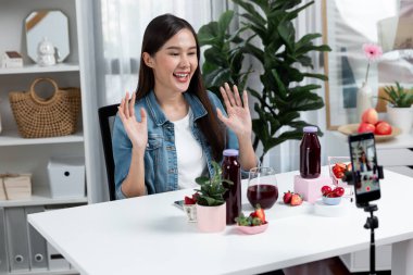 Gülümseyen, güzel Asyalı genç, lezzetli karışık çilek ve kiraz suyu detoksu içeceklerini inceleyen, sosyal medyada özel promosyon satışı için sağlıklı ürünler sergileyen. Taktik.