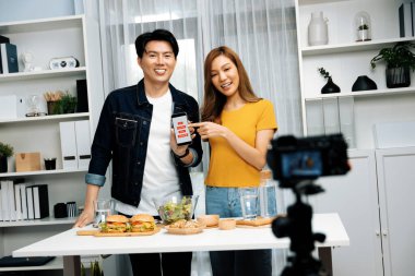 Aşçılar, sosyal medya yemek programı kanalı canlı yayın menü yemeği salatası, kepekli çörek ve video kameradan hamburger kaydı için telefonda yorum okuyorlar. İnfobahn.