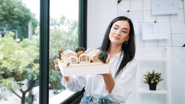 Крупный план квалифицированного молодого красивого кавказского архитектора лифта дом модели левой и правой стороны, чтобы проверить и сосредоточиться на проверке ошибок точки в современном офисе с чертежом. Непорочный.