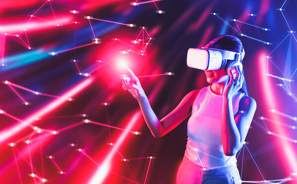 Smart female standing in cyberpunk style building in meta wear VR headset connecting metaverse, future cyberspace community technology, Woman use finger touching virtual reality object. Hallucination.