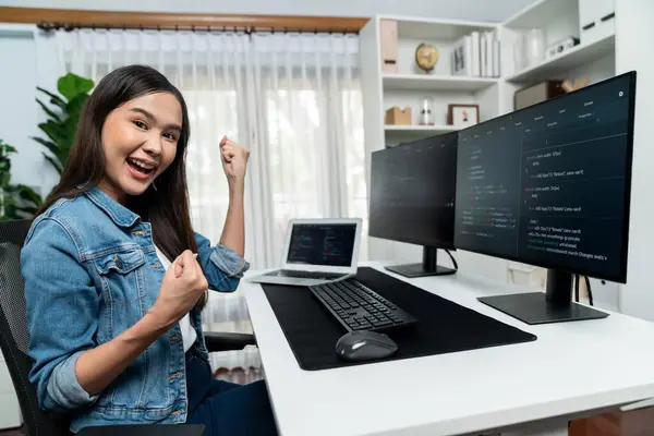 Young Asian IT developer creating raising fist up with successful information on pc with coding program information data application, wearing jeans shirt surround safety analysis screen. Stratagem.