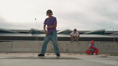 Bir grup Asyalı break dansçı, çok kültürlü arkadaş desteği ve hareketli hip hop müziğiyle sokak dansı yaptılar. Çekici yakışıklı hippi sokak dansında break dansçı. Açık hava sporu 2024. Yumuşak bir şekilde..