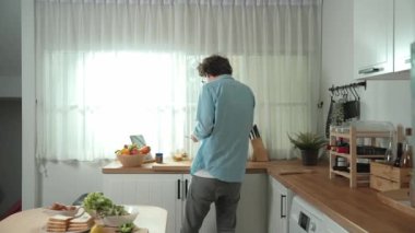 Mutlu baba yemek pişirirken müziğe geçiyor ve modern mutfakta öğle yemeği hazırlıyor. Aktif baba, sebze ve mutfak gereçleri ile çevrili sağlıklı yemek ya da salata yaparken şarkıyla dans ediyor. Pedagoji.