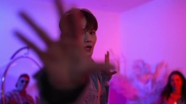 Çok kültürlü bir arkadaş kürsüde otururken Asyalı yetenekli bir dansçı modern müziğe geçiyor. Profesyonel dansçı, hipster takımı tezahürat yaparken ve desteklerken enerjik adımlar atıyor. Mutluluk.