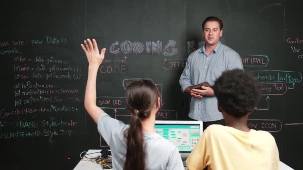 白种人老师回答学生关于编码方案的问题 在Stem技术课上 白人女孩举手提问 志愿者 回答问题 而笔记本电脑显示系统则在屏幕上显示 — 图库视频影像