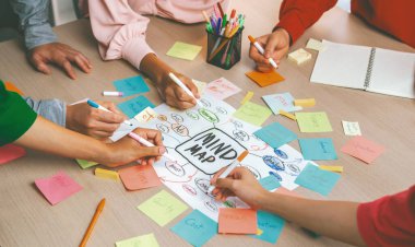 Profesyonel başlangıç grubu zihin haritası kullanarak yaratıcı pazarlama fikrini paylaşıyor. Genç yetenekli iş adamları yapışkan notlar yazarken beyin fırtınası planı yapıyorlar. Eline odaklan. - Yakın çekim. Değiştirilmiş.