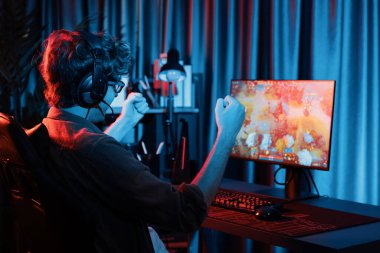 Genç oyun flamasının sunucu kanalı Moba ile savaş meydanında çoklu oyun takımıyla dövüşmeyi kazanıyor, bilgisayar monitöründe kulaklık takıyor ve neon dijital ışık modern odasında arka plan görüntüsü takıyor. Toplayıcı.