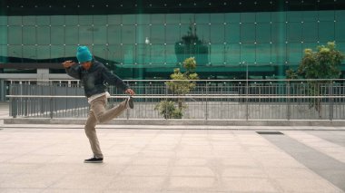 Mutlu hipster canlı bir ruh halinde break dans yaparken kulaklıktan hiphop müzik dinler. Profesyonel sokak dansçısı açık havada break dans yapıyor. Açık hava sporu 2024. Modern yaşam tarzı. Yumuşak bir şekilde..