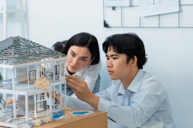 Kooperatif mühendis ekibinin portresi ev modelini ölçmek için cetvel ve mimari ekipmanlar kullanarak birlikte çalışıyor. Yaratıcı iş tasarımı ve takım çalışması konsepti. Tertemiz...