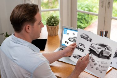 Araba tasarım mühendisi otomobil işi için otomobil prototipini ev ofisinde analiz ediyor. Otomotiv mühendisliği tasarımcısı dikkatle analiz ederek, dizüstü bilgisayarla araba tasarımında kusurlar ve iyileştirmeler buluyor.