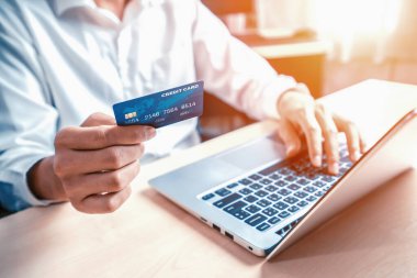 Genç adam, laptop bilgisayar başvurusu ya da web sitesinde online alışveriş yapmak için kredi kartı kullanıyor. E-ticaret ve online alışveriş konsepti. uds