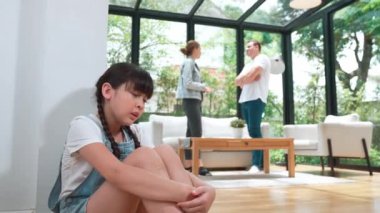Stresli ve mutsuz genç kız köşeye kıvrılıp kulaklarını kapatarak arka planda ebeveyninin tartışmasını engelliyor. Evde aile içi şiddet ve travmatik çocukluk depresyona dönüşür. Titiz