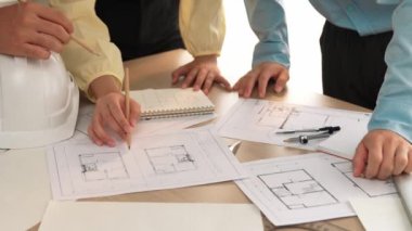 Mimari döküman, ölçüm araçları ve ahşap blokların modern ofiste etrafa saçıldığı masa üzerine planlar yapma konusunda akıllı mimar ve güvenlik mühendisi tartışması. - Yakın çekim. Tanımlama.