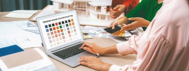 Profesyonel iç tasarımcıların kırpılmış görüntüleri ev modeli ve mimari ekipmanların etrafa saçıldığı proje için renk malzemesi seçiyor. - Yakın çekim. Eline odaklan. Değiştirilmiş.