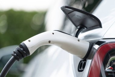 Elektrikli araç portuna bağlı EV şarj prizi kolu şarj istasyonundan şarj oluyor. Modern tasarlanmış EV araba ve daha iyi bir gelecek konsepti için temiz enerji sürdürülebilirliği. Eşzamanlama