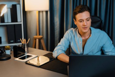 Akıllı iş adamı, gece vakti mavi perde arkasında iş hedefi olan finansal teknoloji veri raporlarını analiz etmek için veritabanı stoklarını araştırmak üzere dizüstü bilgisayarda uzaktan çalışıyor. Bireysel.