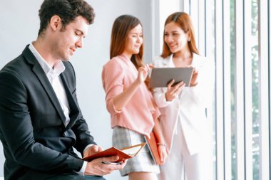 Kitap okuyan ve iş yerinde iş arkadaşları ve arkadaşlarıyla çalışan genç ve yakışıklı bir işadamı. Kurumsal iş adamları grubu. uds