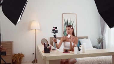 Sosyal medya için güzellik ve kozmetik video içeriği hazırlayan genç bir kadın. Güzellik blogcusu kameraya gülümserken seyircilere ve takipçilere güzellik bakımını gösteriyor. Düzenle