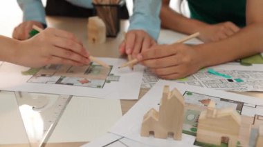 Mimari döküman, ölçüm araçları ve ahşap blokların modern ofiste etrafa saçıldığı masa üzerine planlar yapma konusunda akıllı mimar ve güvenlik mühendisi tartışması. - Yakın çekim. Tanımlama.