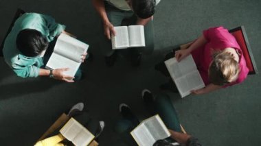 İncil 'i okuyup, kucağında İncil' le daireler çizerek otururken en tepeden aşağı dua manzarası. İnanç, güven ve umut ve sükunetle çalışırken farklı insanların kitaba bakışları. Sempozyum.