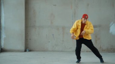 Beyaz hipster sokak, şehir merkezinde ayak sesleri gösteriyor ya da pratik yapıyor. Genç break dansçı hip-hop müziğine ayak basarken hareket ediyor. Açık hava sporu 2024. Gri arka plan. hiphop.
