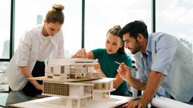 Akıllı mimar takımı ev tasarımı hakkında tartışırken yakışıklı erkek işçi dizüstü bilgisayar kullanarak fikir sunuyor. Profesyonel mühendis paylaşımı, beyin fırtınası tasarımı. İş tasarımı. İzleme