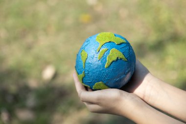 Dünya gezegenini ESG ilkesi ve çevre dostu enerjisiyle daha parlak bir gelecek için Dünya günü olarak el ele tutuşan genç çocuklar. Döngü