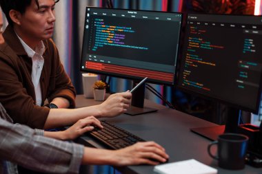 Bilgi teknolojisi geliştiricileri modern ofisteki neon ışık odasında verileri çevrimiçi olarak çalıştıran akıllı web sitesi geliştirme kodlayıcı sistemine işaret ediyorlar. İnfobahn.