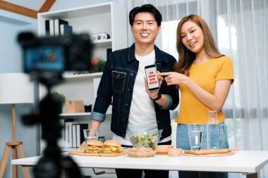 Aşçılar, sosyal medya yemek programı kanalı canlı yayın menü yemeği salatası, kepekli çörek ve video kameradan hamburger kaydı için telefonda yorum okuyorlar. İnfobahn.