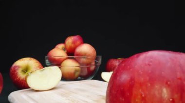 Elmaların makrografisi çeşitli şekillerde sergilenir: bütün, dilimlenmiş ve siyah arka planlı cam bir kase içinde. Her yakın çekim kesme tahtasındaki elmaların kırmızı renklerini yakalar. Geliştirilebilir.