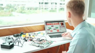 Beyaz öğrenci bilgisayar ekranına bakarken mühendislik komut ya da programlama sistemine bakıyor. Bilgisayarla ve elektronik aletlerle çalışan gençlerin arka plan görüntüsü...
