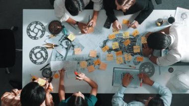 Üstten görünüşlü akıllı mühendis ekibi metal teçhizatlı, hesap makineli, yapışkan notlu türbin motor yapısı hakkında konuşuyor. Bir grup teknisyen toplantıda not alıyor. Hizalama.