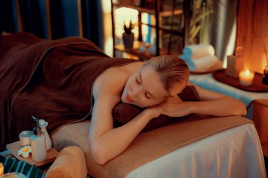 Beyaz kadın müşteri stres önleyici spa masajının keyfini çıkarıyor ve lüks otel ya da otelde sıcak mum ışığında güzellik teniyle eğleniyor. Sessiz.