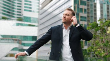 Erkek liderin etrafını sarın kulaklığı dinleyin ve neşeli ve motive edici bir şekilde rahatlatıcı müzikle dans edin. Becerikli proje yöneticisi şehir merkezinde akıllı telefon kullanırken rahat şarkılar dinlemeyi sever. Urbane.