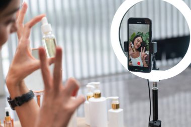 Sosyal medya için güzellik ve kozmetik video içeriği hazırlayan genç bir kadın. Güzellik blogcusu seyirciye güzellik hizmetini nasıl uygulayacağını ya da kamera karşısında takipçiyi nasıl izleyeceğini gösteriyor. Blithe