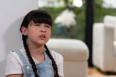 Oturma odasında yalnız başına oturup ağlayan, kendini yalnız hisseden üzgün küçük kız. Sosyal izolasyon cezası alan ya da ebeveynlerinden ihmal edilen genç bir kız çocukluğunda endişe ve travmaya yol açtı. Eşzamanlama