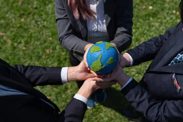 Group of business people hold planet Earth globe together as Earth day concept. Mission to save Earth by business commitment to environment friendly methods and sustainable practices. Gyre