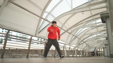 Profesyonel hippi kulaklık takıyor ve hip hop müzik dinleyip hip hop dansı yapıyor. Çekici, yakışıklı break dansçı dondurucu poz veriyor. Sokak dansı. Açık hava sporu 2024. Yumuşak bir şekilde..
