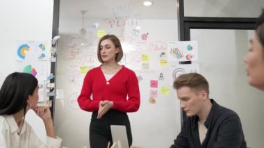 Yetenekli genç ve güzel iş kadını, yaratıcı iş toplantısında yakışıklı yönetici dinlerken zihin haritalama ve istatistiksel grafik kullanarak pazarlama fikrini kendine güvenle sunuyor. Tertemiz..