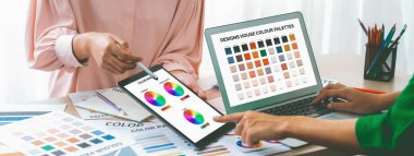 Profesyonel tasarımcının kırpılmış bir resmi, dizüstü bilgisayarın rengi ile etraftaki malzeme ve ekipman dağılımını karşılaştırırken renk teorisini kullanarak rengi seçer. Değiştirilmiş.