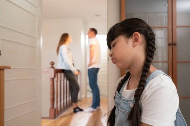 Stresli ve mutsuz genç kız arka planda ebeveynleri tartışırken köşede ağlayıp üzülüyor. Evde aile içi şiddet ve travmatik çocukluk depresyona dönüşür. Eşzamanlama