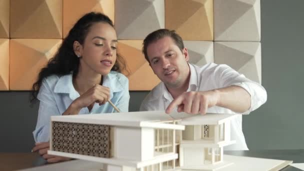 専門の建築家エンジニアのチームは家のモデルの構造について論議します 家の材料および構造問題についての熟練したプロジェクト マネージャーのブレインストーミング ビジネスデザインコンセプト マニピュレーター — ストック動画