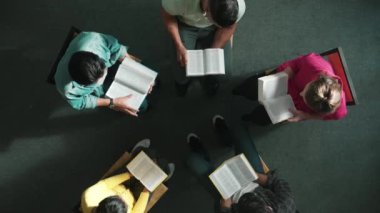 İncil 'i okuyup, kucağında İncil' le daireler çizerek otururken en tepeden aşağı dua manzarası. İnanç, güven ve umut ve sükunetle çalışırken farklı insanların kitaba bakışları. Sempozyum.