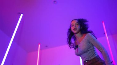 Latin dansçıların kameraya bakıp şehrin pop müziğiyle dans ettiği düşük açılı kamera. Profesyonel çekici hipster, mor veya neon ışıklı hip hop şarkısına geçiyor. Şık bir kumaş. Mutluluk.