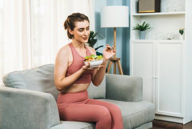 Spor giyimli sağlıklı ve vejetaryen bir kadın bir kase meyve ve sebzeyle. Sağlıklı beslenme ve spor için vejetaryen yaşam tarzı ev konseptinde vücut fiziği.